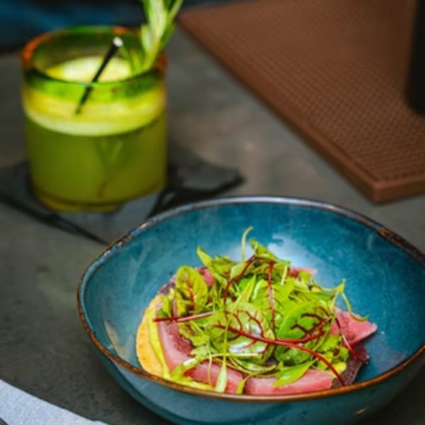 Chicatana's tuna tostada with greens in a blue bowl, next to a green drink.
