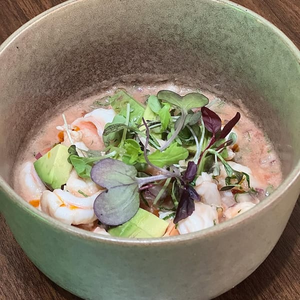 Chicatana's shrimp ceviche with avocado and microgreens in a rustic green bowl.
